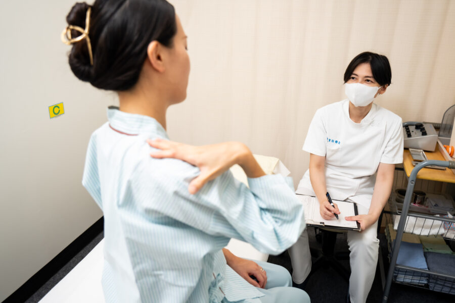 肩が辛い患者様と問診中の鍼灸師